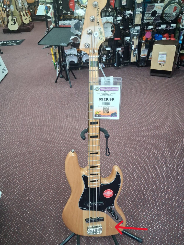 Electric bass guitar on display with a price tag in a music store showing minor blemishes on the body