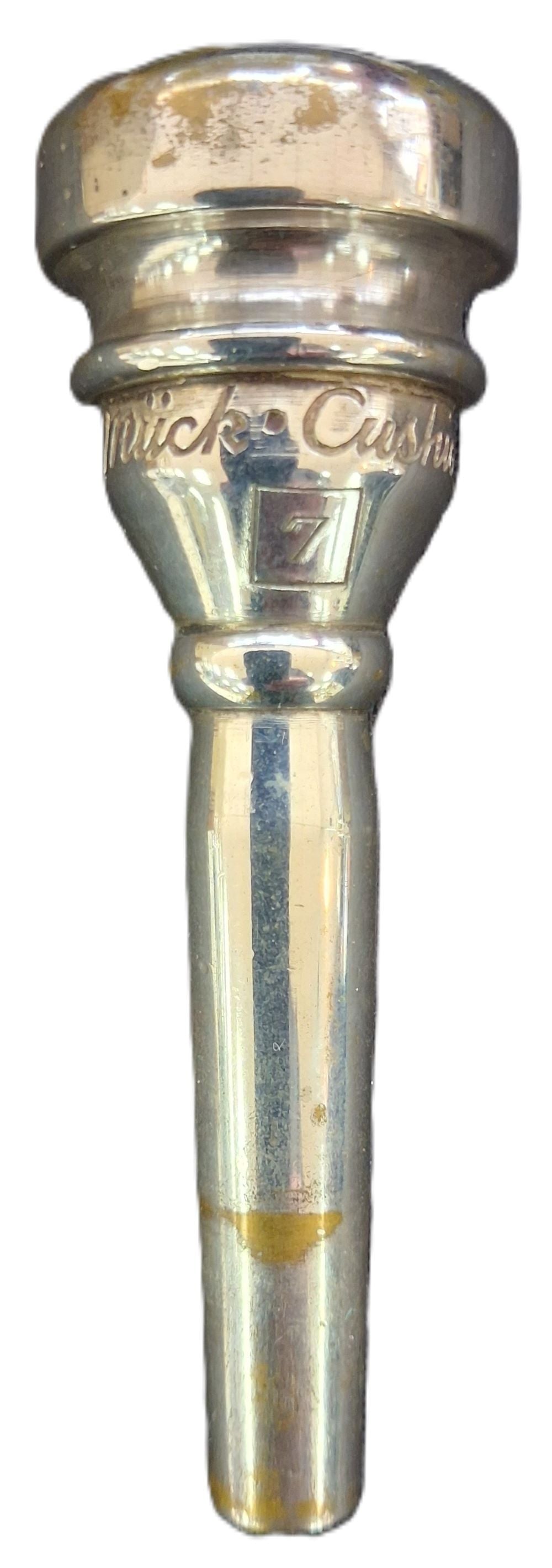 A silver metallic trumpet mouthpiece with engraved text reading 'Rudy Muck 7' and a size marking,